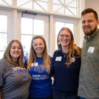 Alumni smile at camera in the Alumni House and Visitor Center